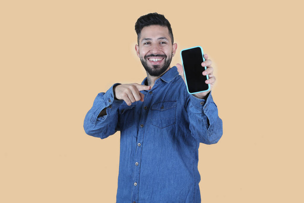 hombre latino hispano en camisa señala su teléfono feliz - Foto, imagen