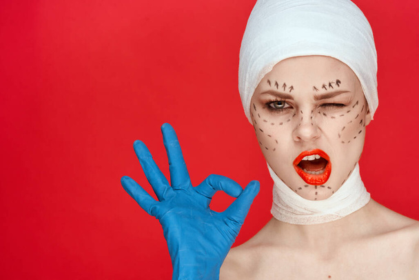 beautiful woman in blue gloves syringe in hands contour on the face lifting red background - Fotoğraf, Görsel