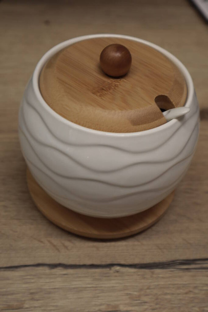 Una zuccheriera in ceramica con coperchio in legno poggia su uno stand sul tavolo. - Foto, immagini