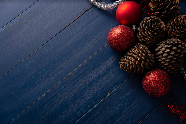 Pine cones and red christmas balls for christmas decoration on vintage blue wood background. Copy space for your text - Photo, Image