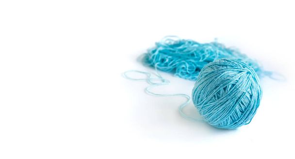 A ball of blue fine cotton yarn in the process of winding on the white background. Tangled yarn in the background. Banner with space for text on the left  - Photo, Image