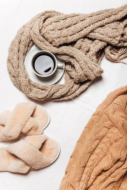 теплый шарф, вязаный свитер, чашка кофе и тапочки на белом фоне - Фото, изображение