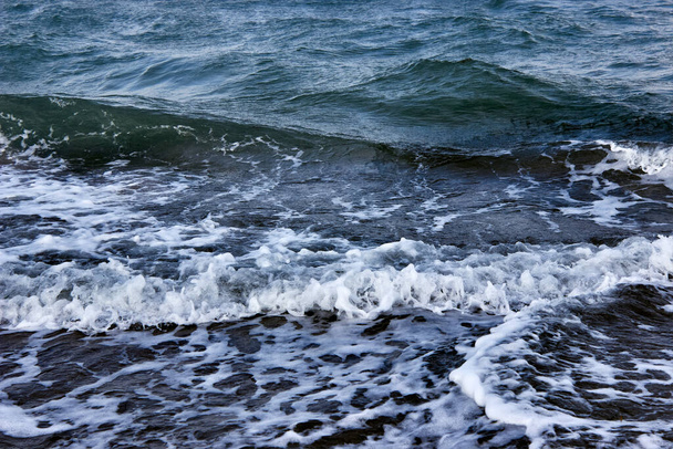 Ondas en la superficie del agua. Mar oscuro, olas fuertes con espuma blanca brillante del mar. El mar furioso con mal tiempo. Una ola entrante de cerca. Olas de tormenta en el mar. Fondo natural abstracto.  - Foto, imagen