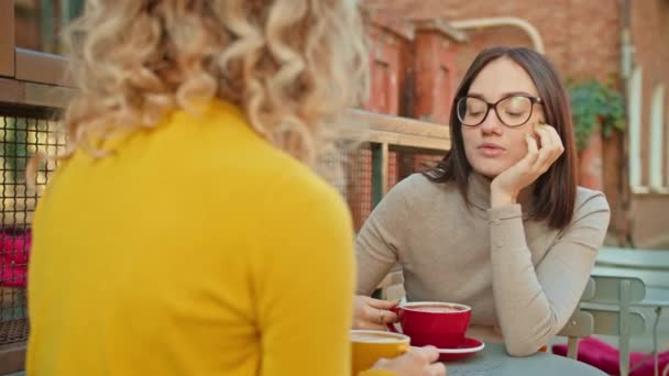 Kobiety rozmawiają i piją kawę przy stole na ulicy w jesienny dzień - Materiał filmowy, wideo