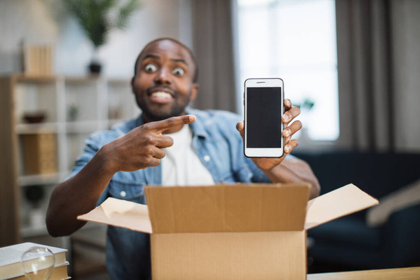Male blogger opening parcel with new smartphone - Foto, Imagem