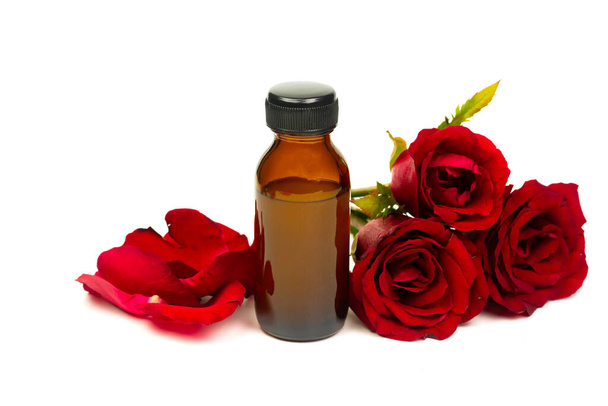 Rose oil in glass bottle with red rose flower isolated on white background. Essential oil product concept. - Foto, Imagen
