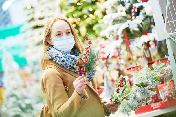 christmas decoration shopping. woman in mask buying new year decor in shop - 写真・画像