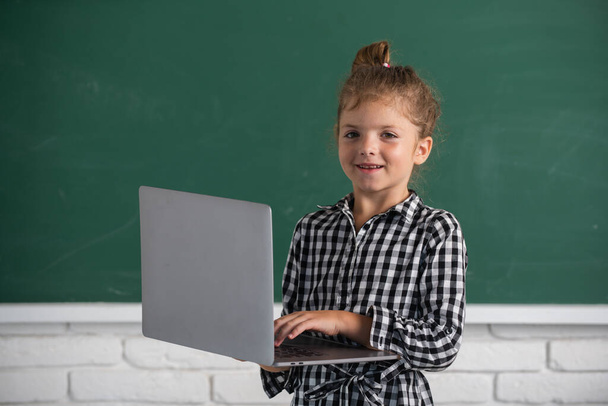 Cute little school kid girl study in a classroom. Online learning technology. - Фото, зображення