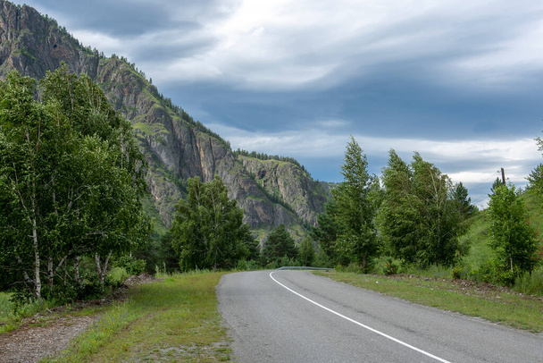 asphalt road between mountain peaks. warm summer day - Foto, afbeelding