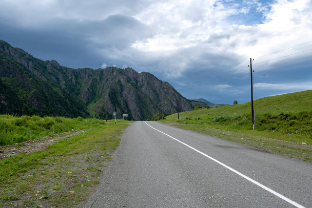 asphalt road between mountain peaks. warm summer day - 写真・画像