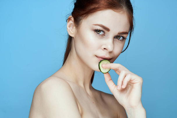 woman with bare shoulders cucumber vitamins health blue background - Foto, afbeelding