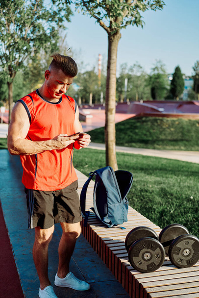 athletic man in red t-shirt in fitness park - Photo, image