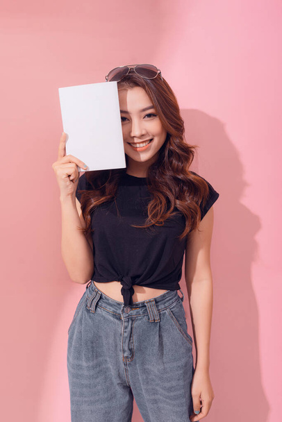ポートレート若いです幸せなアジアの女性の本カバーあなたの目笑顔正の感情上のピンクの背景 - 写真・画像