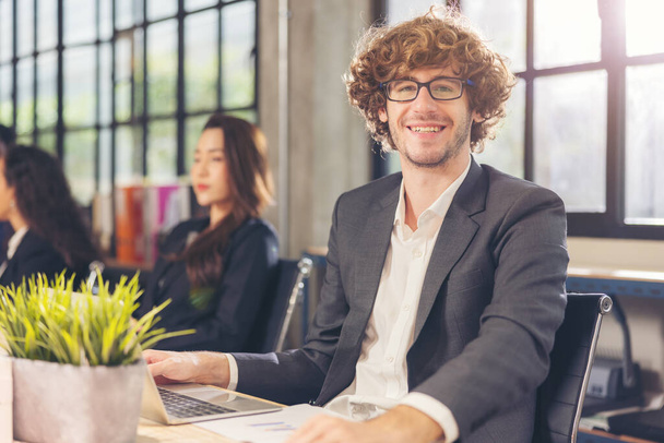 Egy boldog kaukázusi férfi portréja, aki egy céges üzleti katalógusban pózol munkatársakkal a háttérben egy fotózáson az irodában.. - Fotó, kép