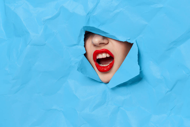 womans face breaks through blue mockup close-up - Foto, Imagem