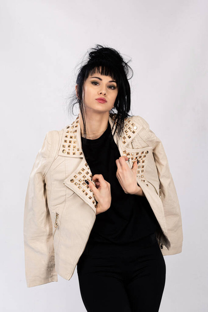 A vertical shot of a young Caucasian female in a leather jacket posing on isolated white background - Photo, Image