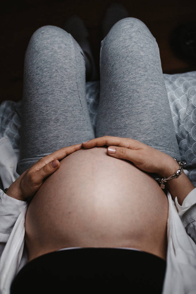 A vertical shot of a pregnant woman holding her belly - Valokuva, kuva
