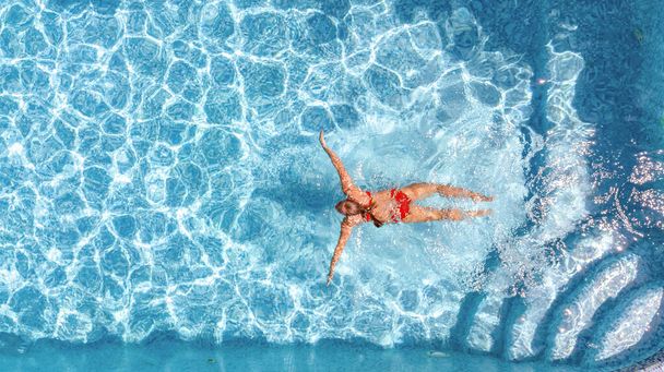 Активная молодая девушка в бассейне беспилотник вид сверху, молодая женщина плавает в бассейне с голубой водой, тропический отдых на курорте  - Фото, изображение