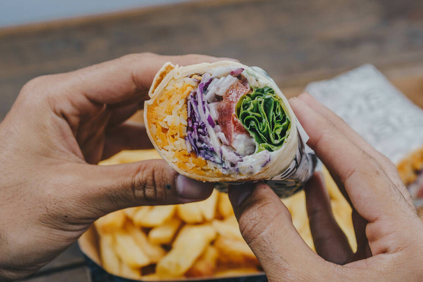 A pair of hands holding a delicious vegetable wrap - Foto, Imagen