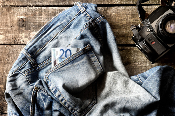 paar van vuile jeans, twintig euro bill en vintage camera - Foto, afbeelding