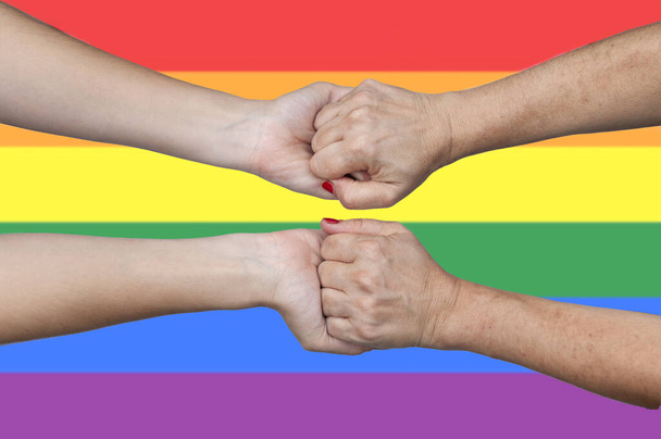 A closeup shot of holding hands on LGTB flag background - 写真・画像