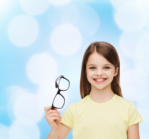 smiling cute little girl holding black eyeglasses - 写真・画像
