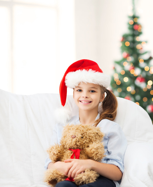 smiling girl in santa helper hat with teddy bear - Foto, Bild