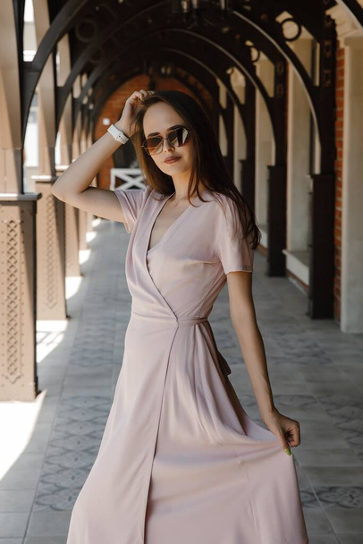 young woman in beige dress and brown sunglasses on the street - Foto, imagen