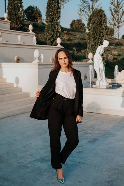 young woman in black trouser suit and silver shoes on the background of the park - Φωτογραφία, εικόνα