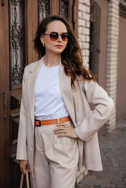 young woman in white pantsuit and white t-shirt in city location - Fotó, kép