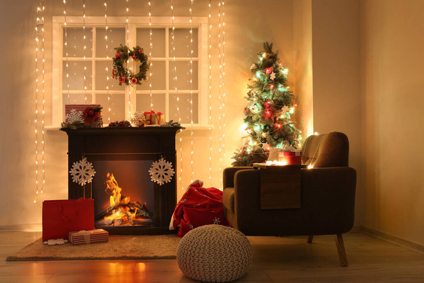 Interieur woonkamer met open haard, kerstboom en gloeiend licht - Foto, afbeelding