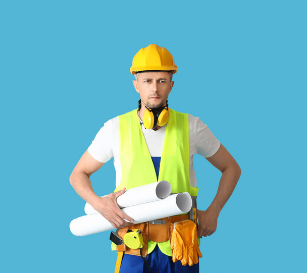Male builder with drawings on color background - Photo, Image
