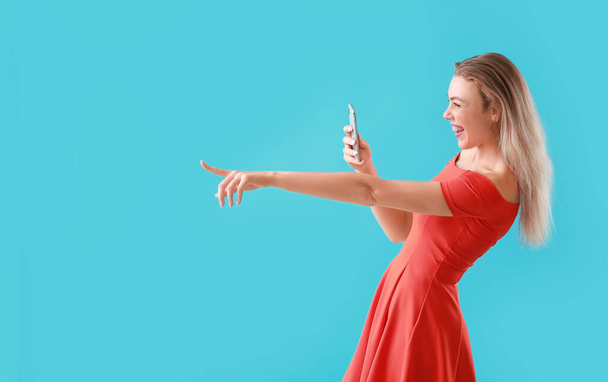 Junge Klatschfrau mit Handy auf farbigem Hintergrund - Foto, Bild
