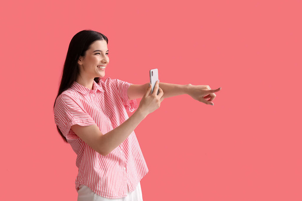 Young gossiping woman with phone on color background - Photo, Image