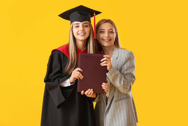 Щаслива студентка-випускниця з матір'ю на кольоровому фоні
 - Фото, зображення