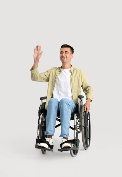 Jovem em cadeira de rodas acenando mão no fundo claro - Foto, Imagem