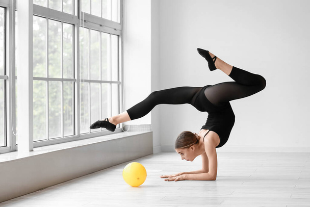 Όμορφη νεαρή γυναίκα κάνει γυμναστική με μπάλα στο γυμναστήριο - Φωτογραφία, εικόνα