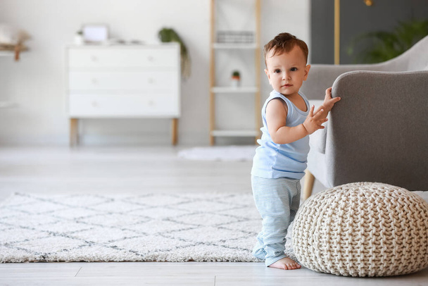 Pieni vauva poika oppii kävelemään lähellä sohvaa kotona - Valokuva, kuva