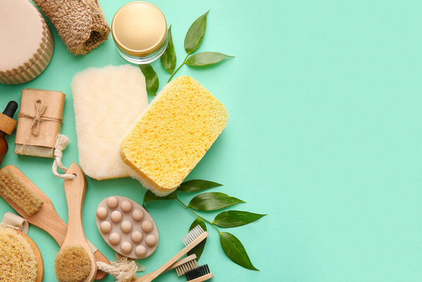 Set of bath supplies with sponges and plant branches on green background - Fotoğraf, Görsel