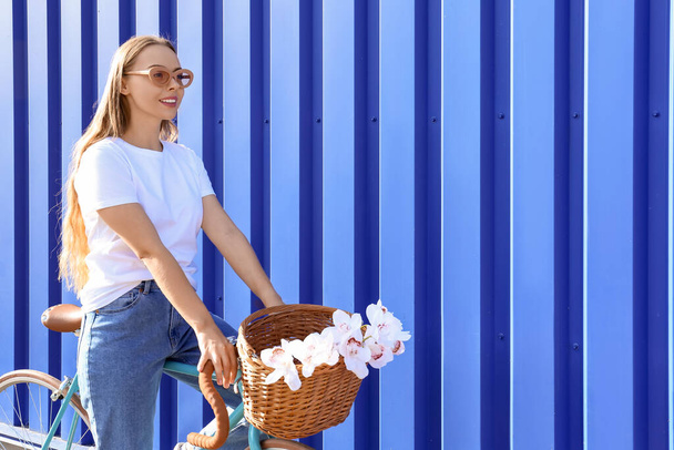 Pretty teenage girl in sunglasses with bicycle near blue fence - Zdjęcie, obraz