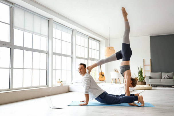 Urheilullinen pari harjoittelee joogaa kotona - Valokuva, kuva