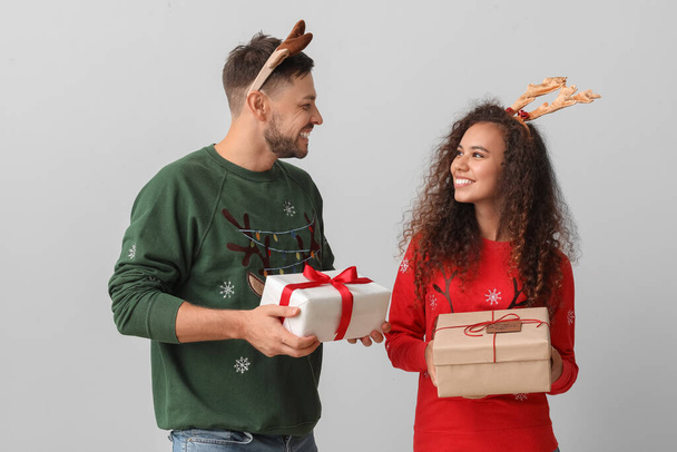Ευτυχισμένο ζευγάρι με χριστουγεννιάτικα δώρα σε ανοιχτόχρωμο φόντο - Φωτογραφία, εικόνα