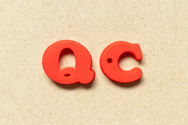 Plastic alphabet letter in word QC (Abbreviation of Quality Control) on wood background - Фото, зображення