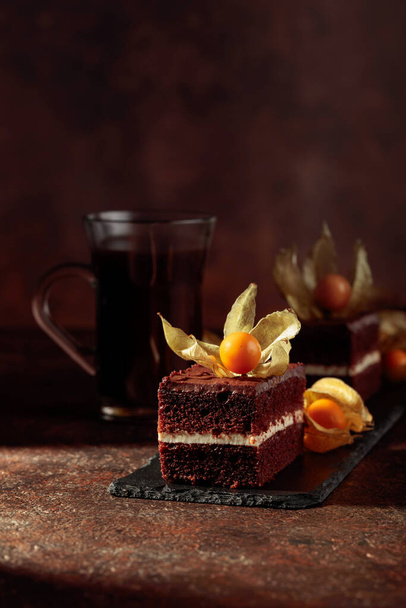 Chocolate cake with physalis on a brown background. Copy space. - Valokuva, kuva