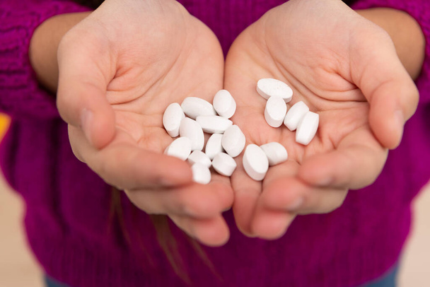 Egy halom gyógyszerészeti orális gyógyszer tabletta vagy gyermekgyógyászati vitaminok gyermekeknél kezekben, tablettákban - Fotó, kép