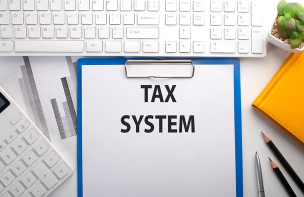 Налоговая система написана на бумаге с клавиатурой, графиком, калькулятором и ноутбуком - Фото, изображение