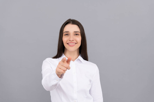 sonriente mujer de negocios en camisa blanca señalando el dedo sobre fondo gris, ceo - Foto, imagen