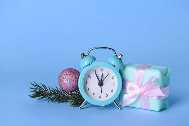 Alarm clock, fir branch and gift on blue background - Photo, Image
