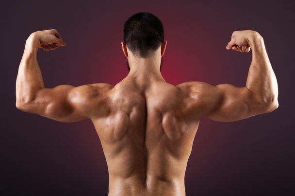 Jeune bodybuilder montrant ses muscles du dos sur un fond sombre
 - Photo, image