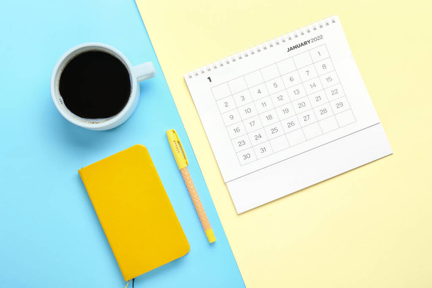 Kalendarz Flip papieru na styczeń 2022, notatnik, długopis i filiżanka kawy na tle koloru - Zdjęcie, obraz